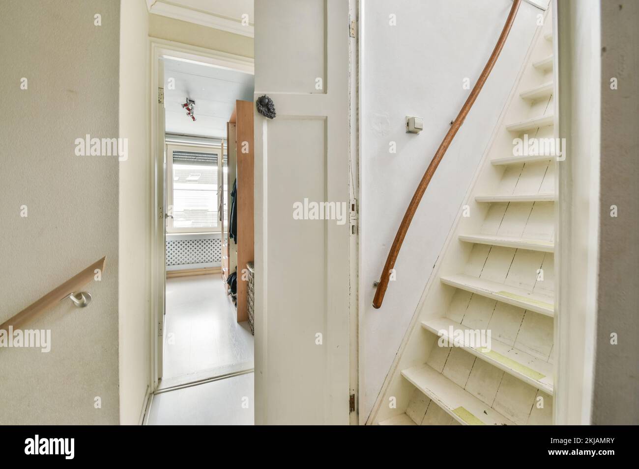 Light narrow hallway with door and radiator in white walls and glowing ...