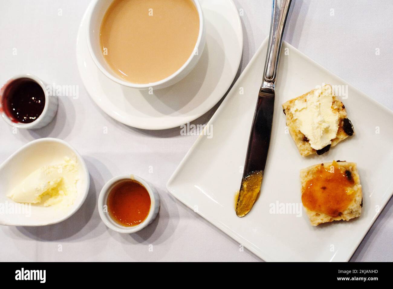Tea and a raisin scone, served with a choice of jam and spread with clotted cream, at high tea in Hong Kong. Stock Photo