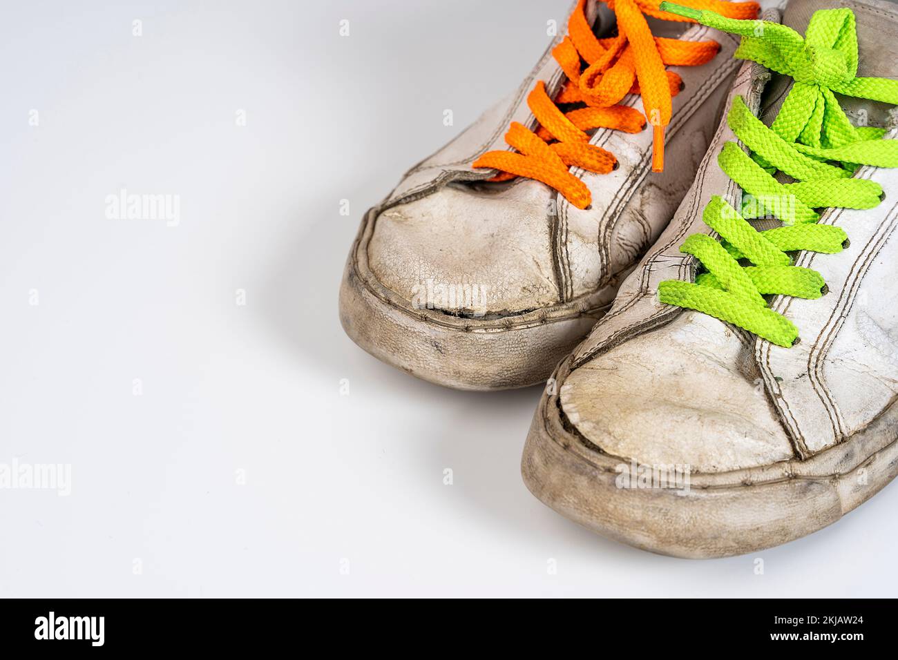 worn old torn white sneakers with colored laces on a white background ...