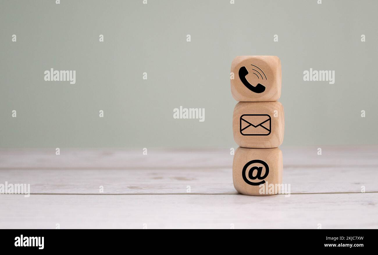 A wooden cube with communication icons on it: a telephone receiver, a ...