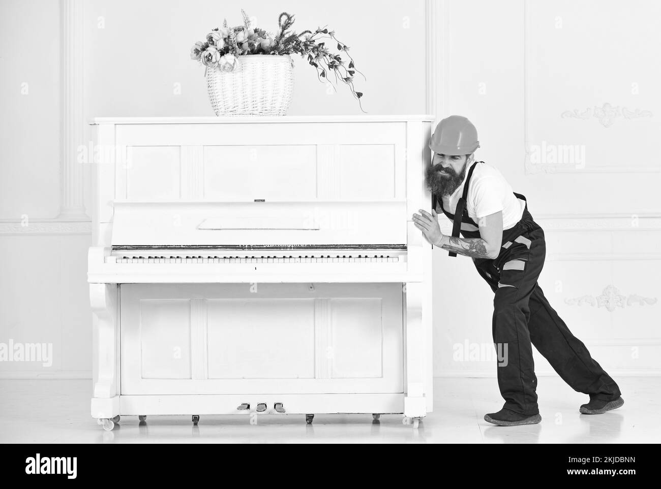 Mover frowning while moving heavy piano. Tired guy relocating stuff in the apartment isolated on