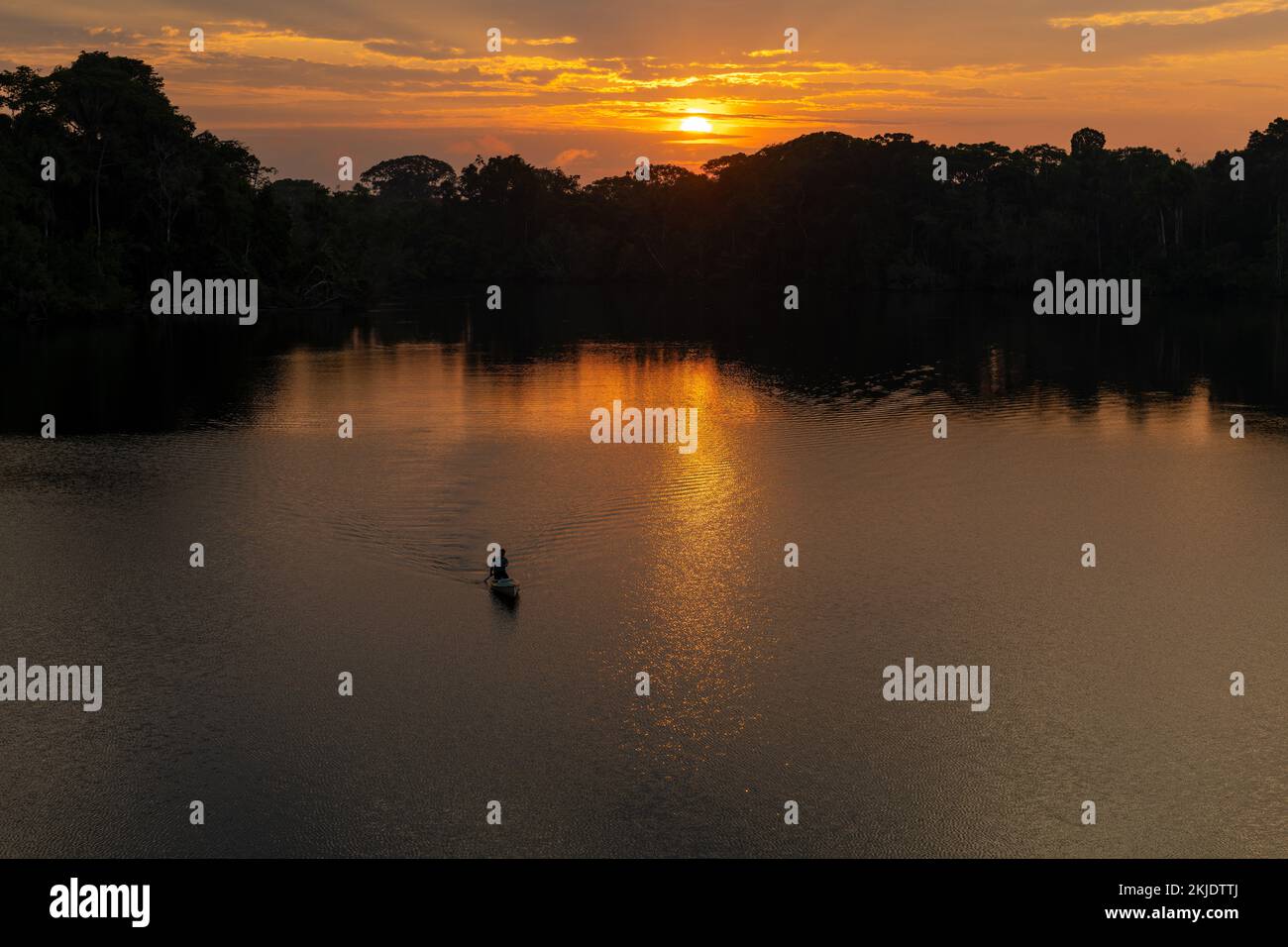 Man silhouette in canoe at sunrise, Amazon rainforest. Amazon river basin in Brazil, Peru, Ecuador, Bolivia, Guyana, Venezuela, Colombia, Suriname. Stock Photo