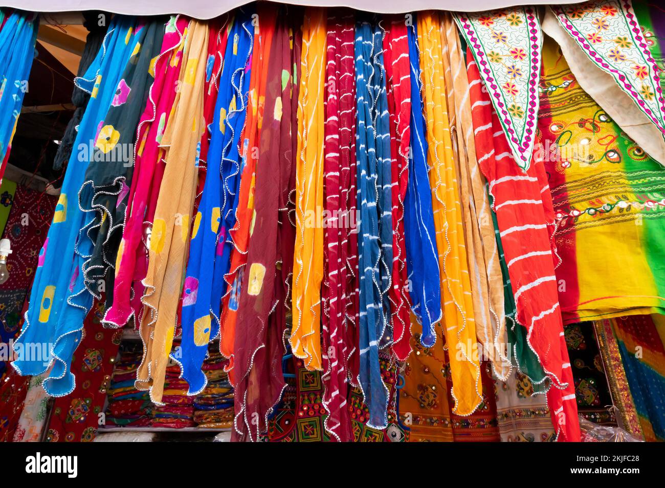 Rajasthani womens clothes are hanging for sale , being displayed in a shop at famous Sardar Market and Ghanta ghar Clock tower in the evening. Stock Photo