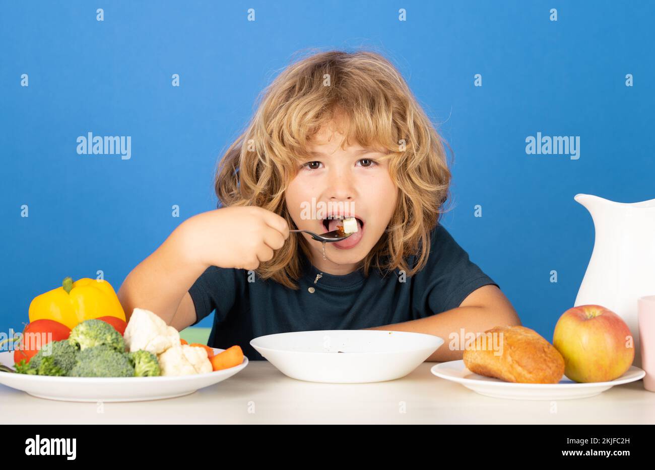 Healthy breakfast lunch for kids. Child eating healthy food on studio iosolated background. Baby eat soup with spoon. Kid eating soup. Stock Photo
