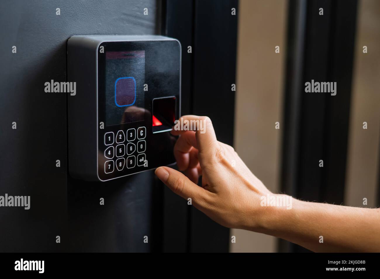 A woman opens the door with her fingerprint. Modern keyless entry lock.  Stock Photo