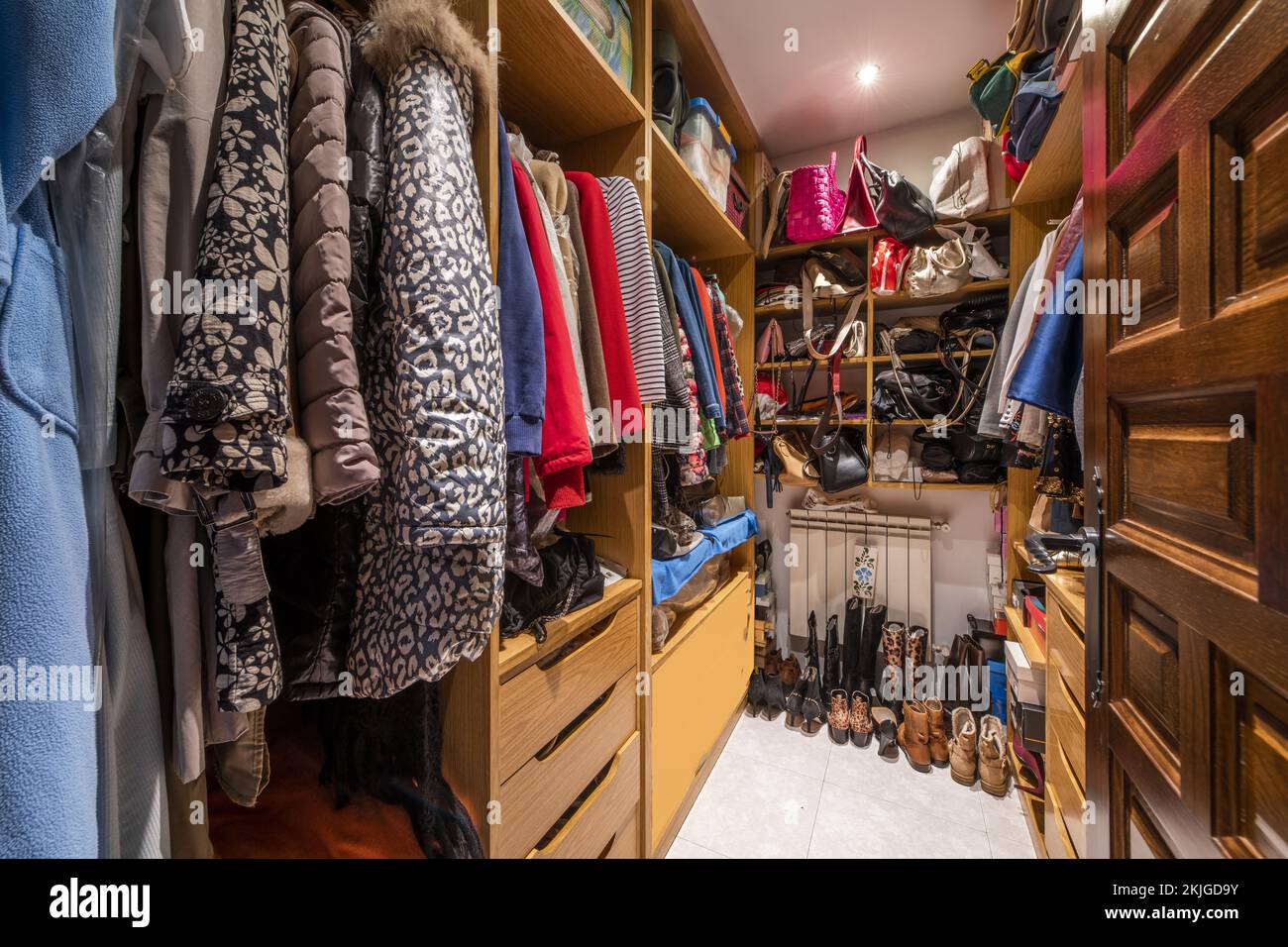 walk-in closet with wooden shelves, drawers and full of clothes on the hangers Stock Photo