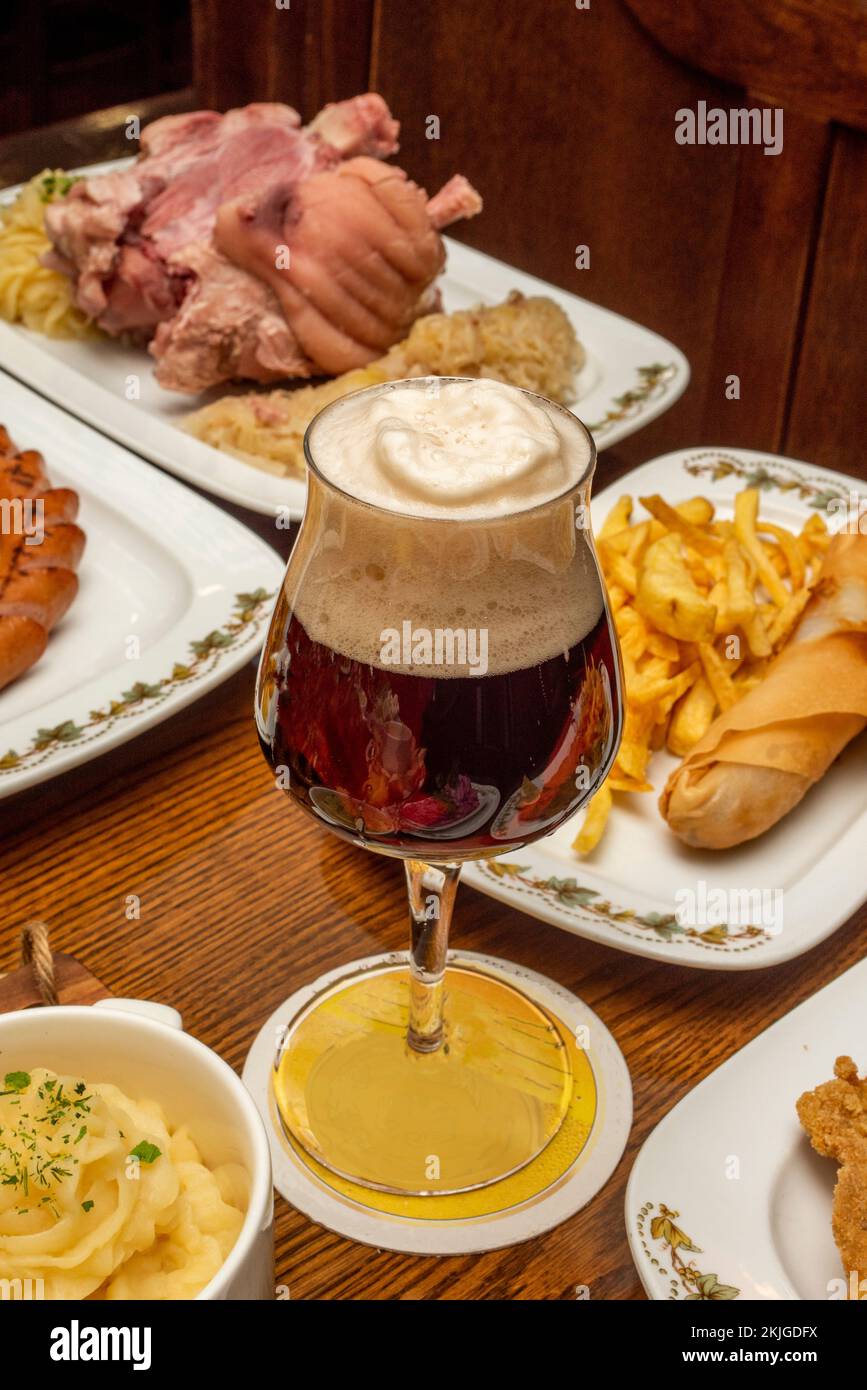 Glass of strong German beer surrounded by typical dishes of its gastronomy Stock Photo