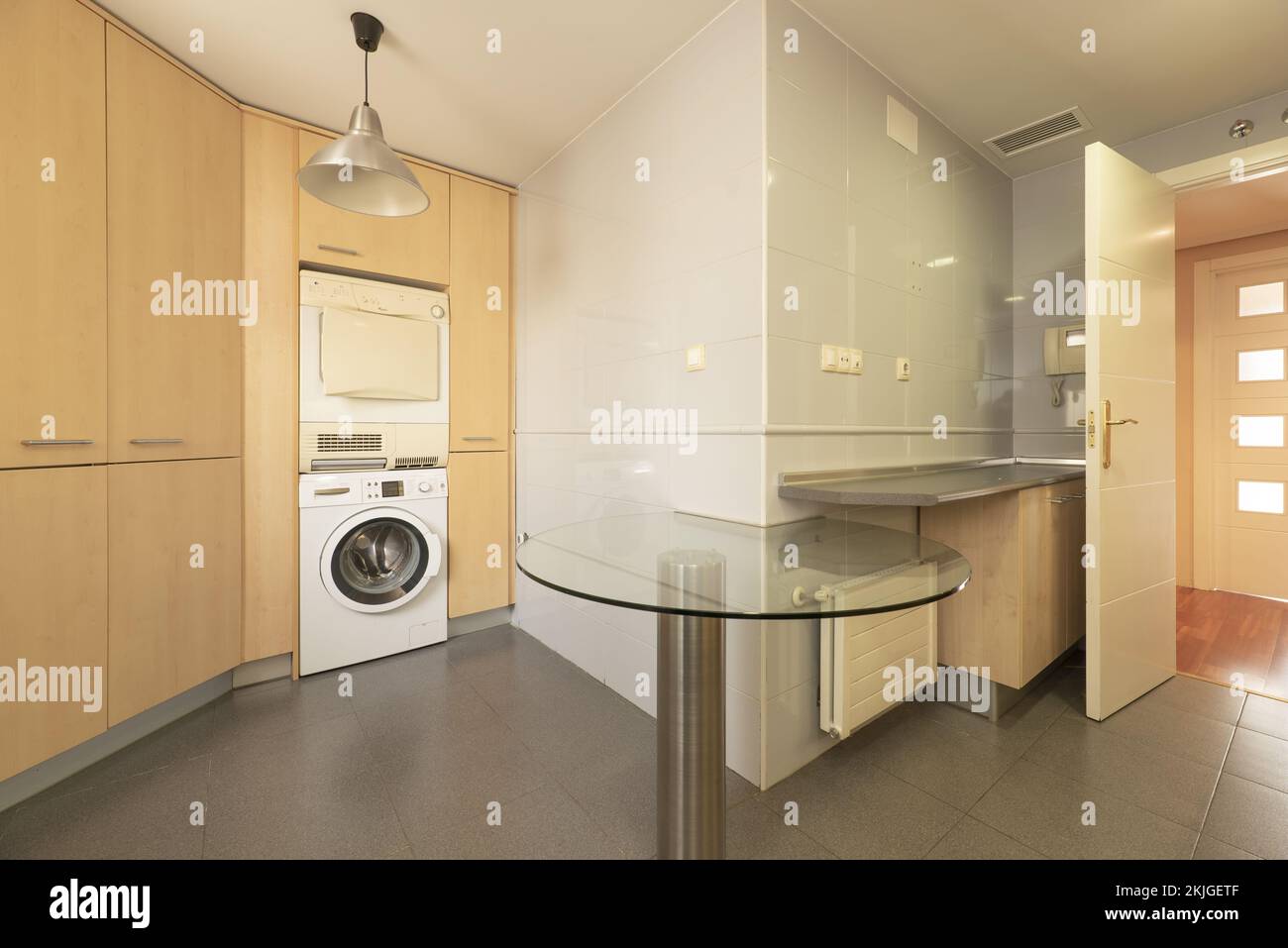 Corner of a kitchen with column cabinets in beech wood color and