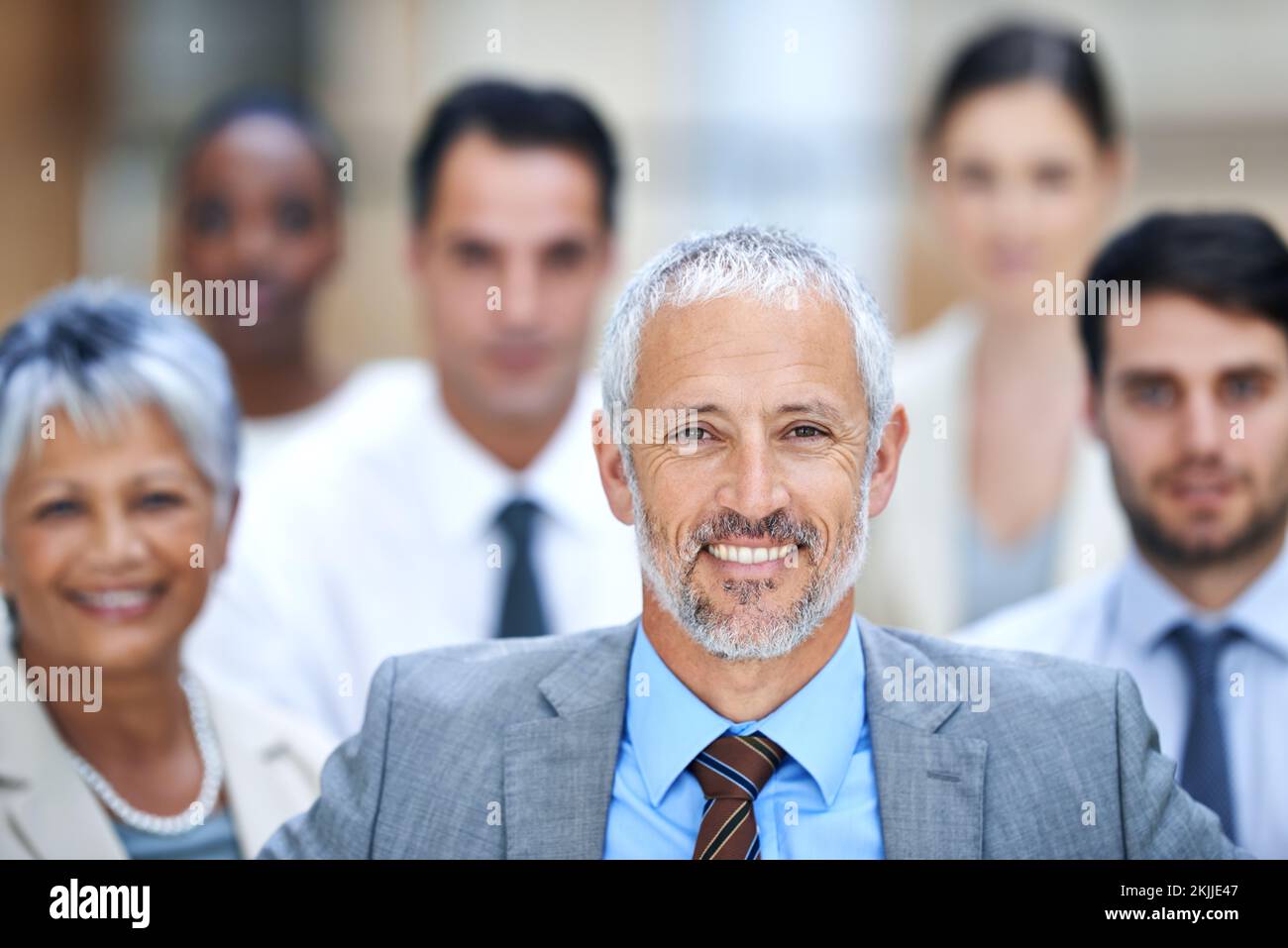 We never allow failure to stand in our way. Portrait of a smiling businessman surrounded by a group of his colleagues. Stock Photo