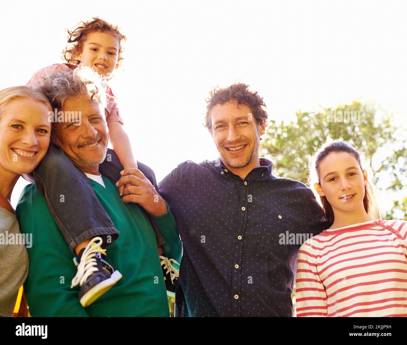 Three generations coming together. Portrait of a family standing outdoors in the sun. Stock Photo