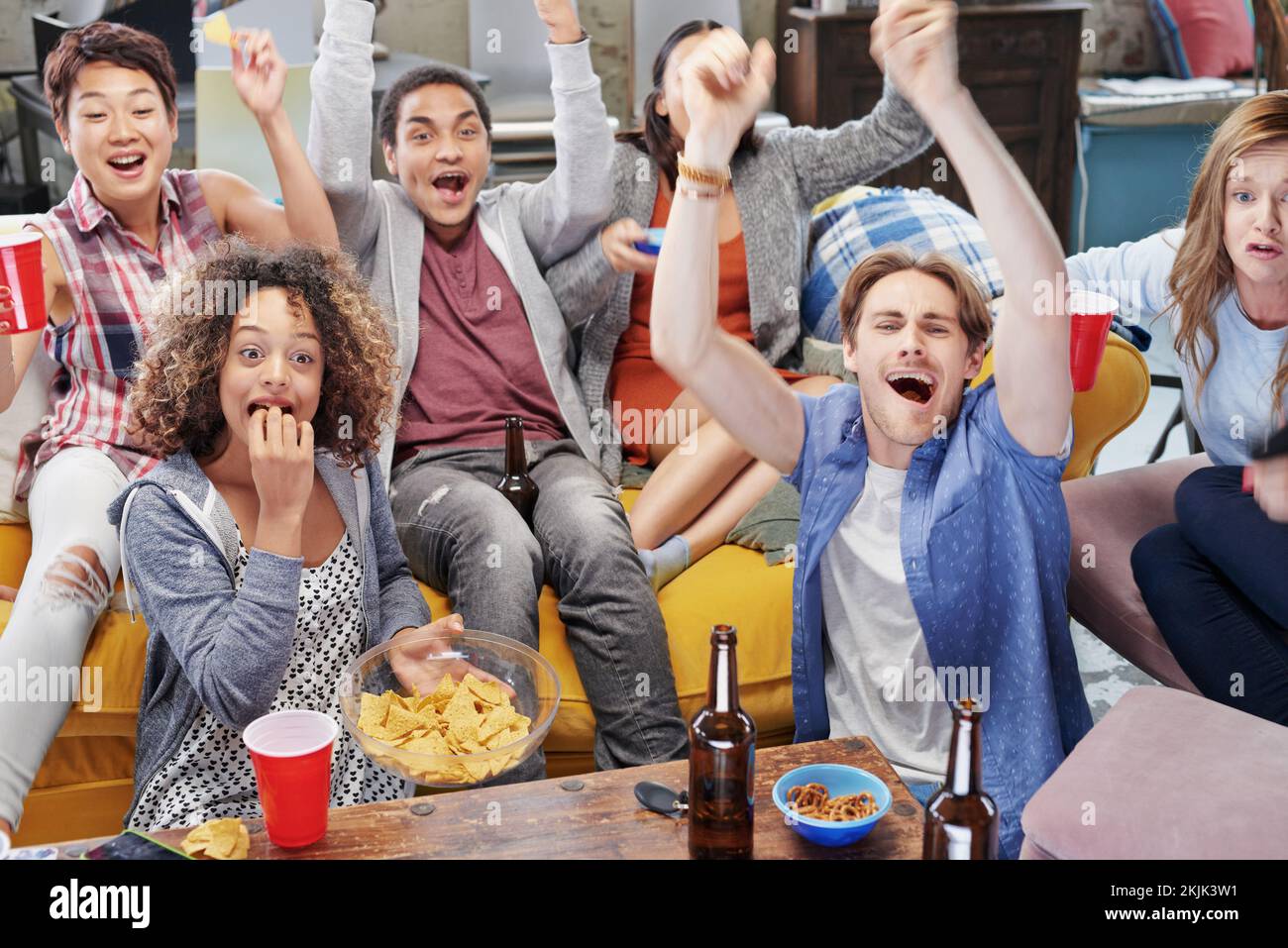Food, party and watching tv with friends in living room for sports games, winner and goal with global Fifa world cup. Diversity, support and wow with Stock Photo