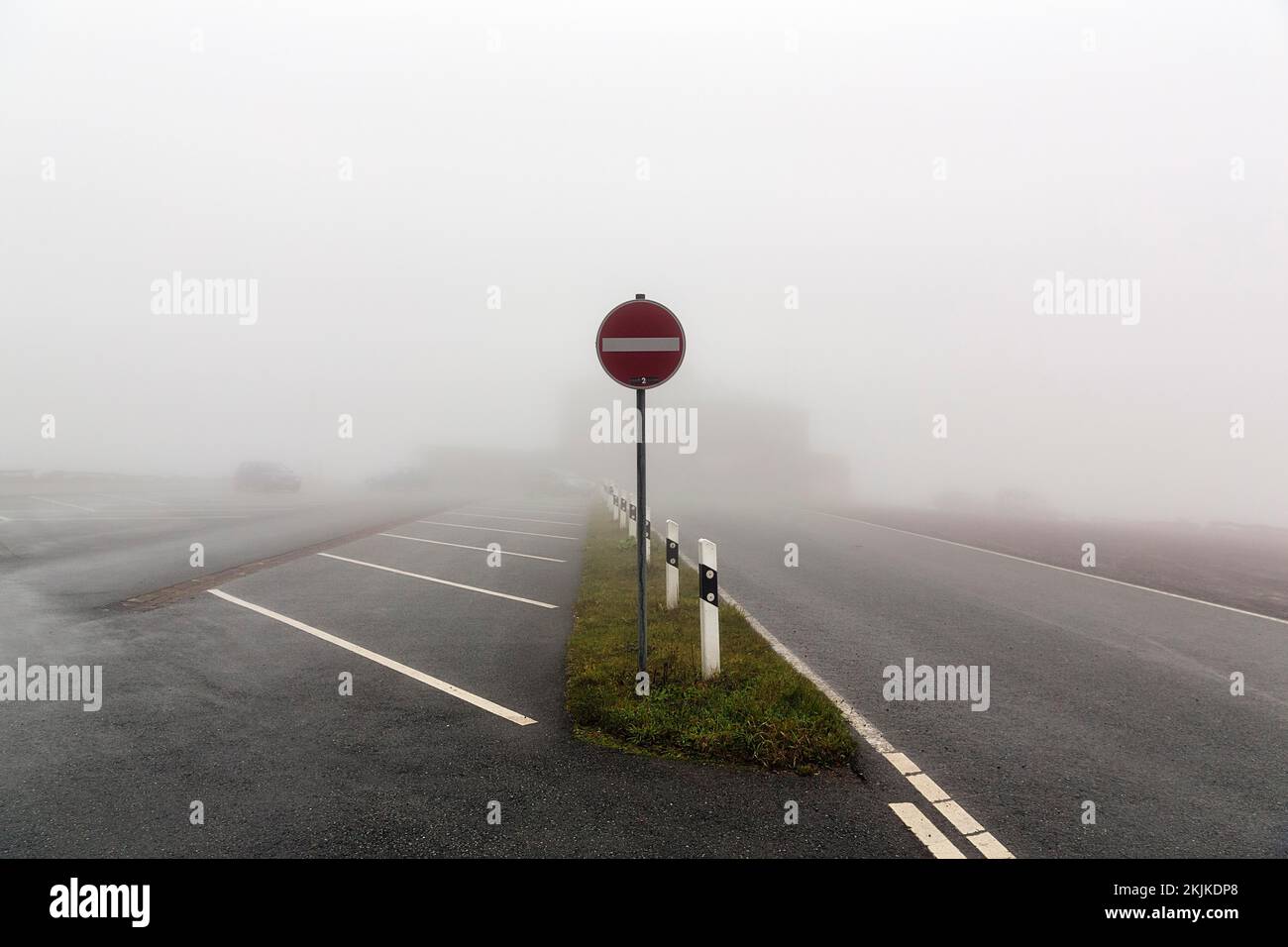 Empty car park at Köterberghaus with one-way street sign, dreary autumn weather with fog, mountain peak, Köterberg, Lügde, Weserbergland, North Rhine- Stock Photo