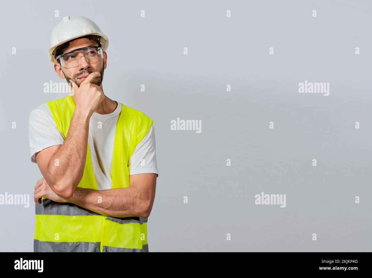 Pensive builder man with hand on chin, Portrait of young builder thinking with hand on chin isolated, A pensive engineer on white background. Concept Stock Photo