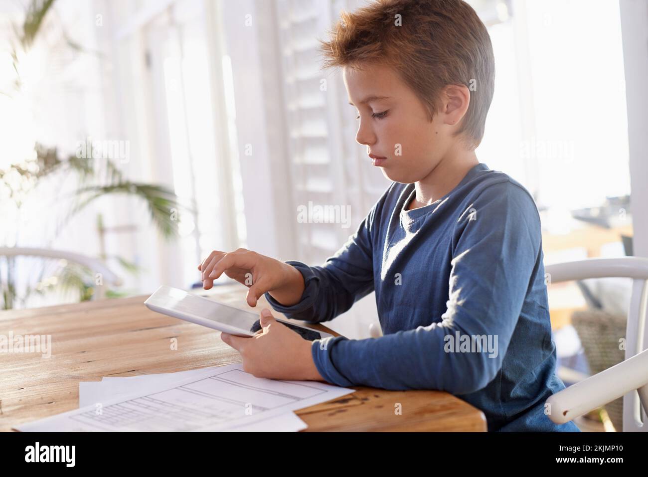 A very efficient homework session. a young boy using a digital tablet to do his homework. Stock Photo