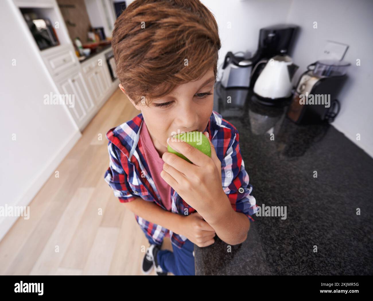Healthy snacking recommended by Mom. a young boy biting into an apple. Stock Photo