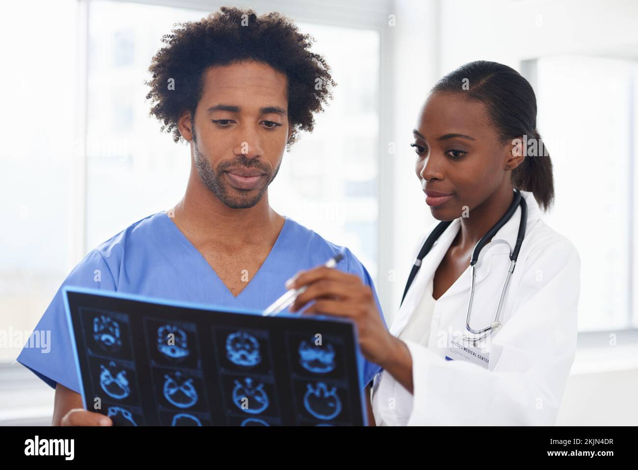 Shes great at explaining the scans. a female African American doctor and male nurse studying a CAT scan. Stock Photo