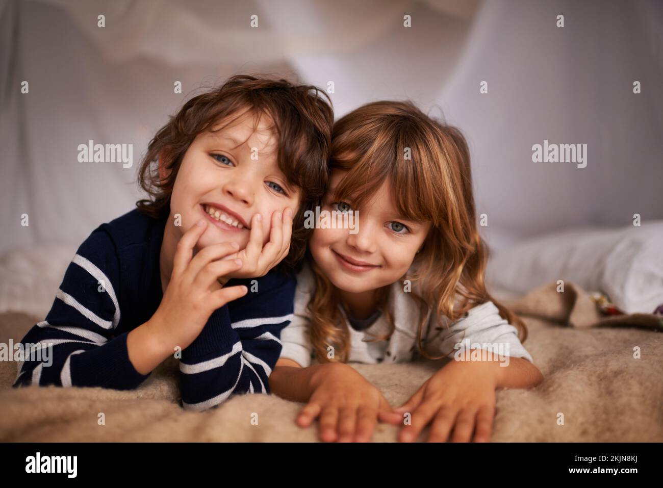 My sister has the best brother ever. Portrait of two adorable siblings lying underneath a fort. Stock Photo
