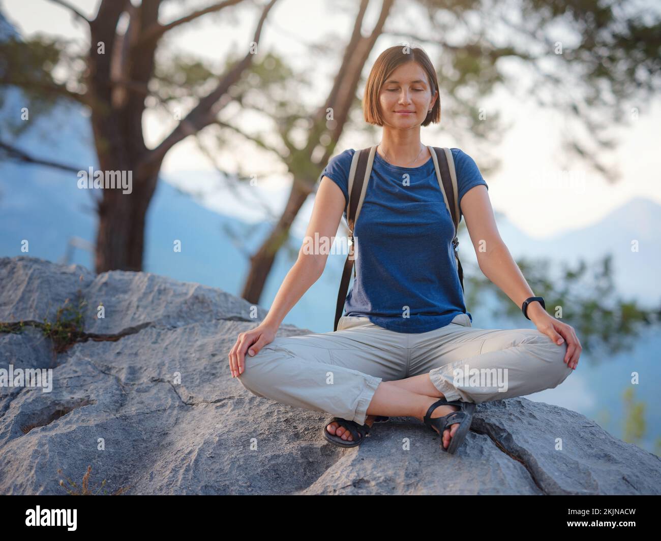 Woman doing yoga in Hawaii mountains. Asian girl meditating in tree pose  with praying hands above head standing on one leg in Kauai, Hawaii, USA.  girl in serene nature landscape. Stock Photo