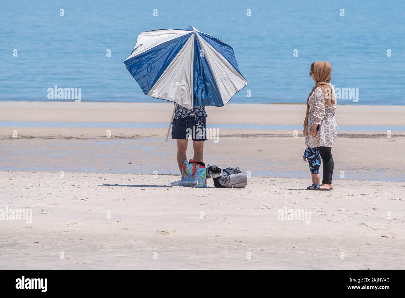 Adelaide, Australia. 25 November 2022.  A man adjusts a sun parasol today during the  the hot weather at the beach in Adelaide Australia as temperatures are forecast to reach above 30celsius. Credit: amer ghazzal/Alamy Live News Stock Photo