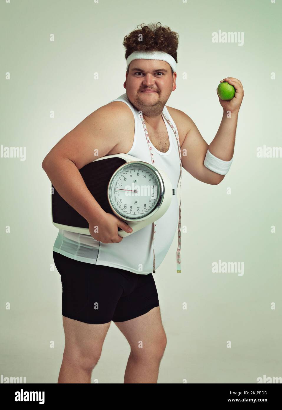 Lets do this. an overweight man holding a apple,scale and measuring tape. Stock Photo