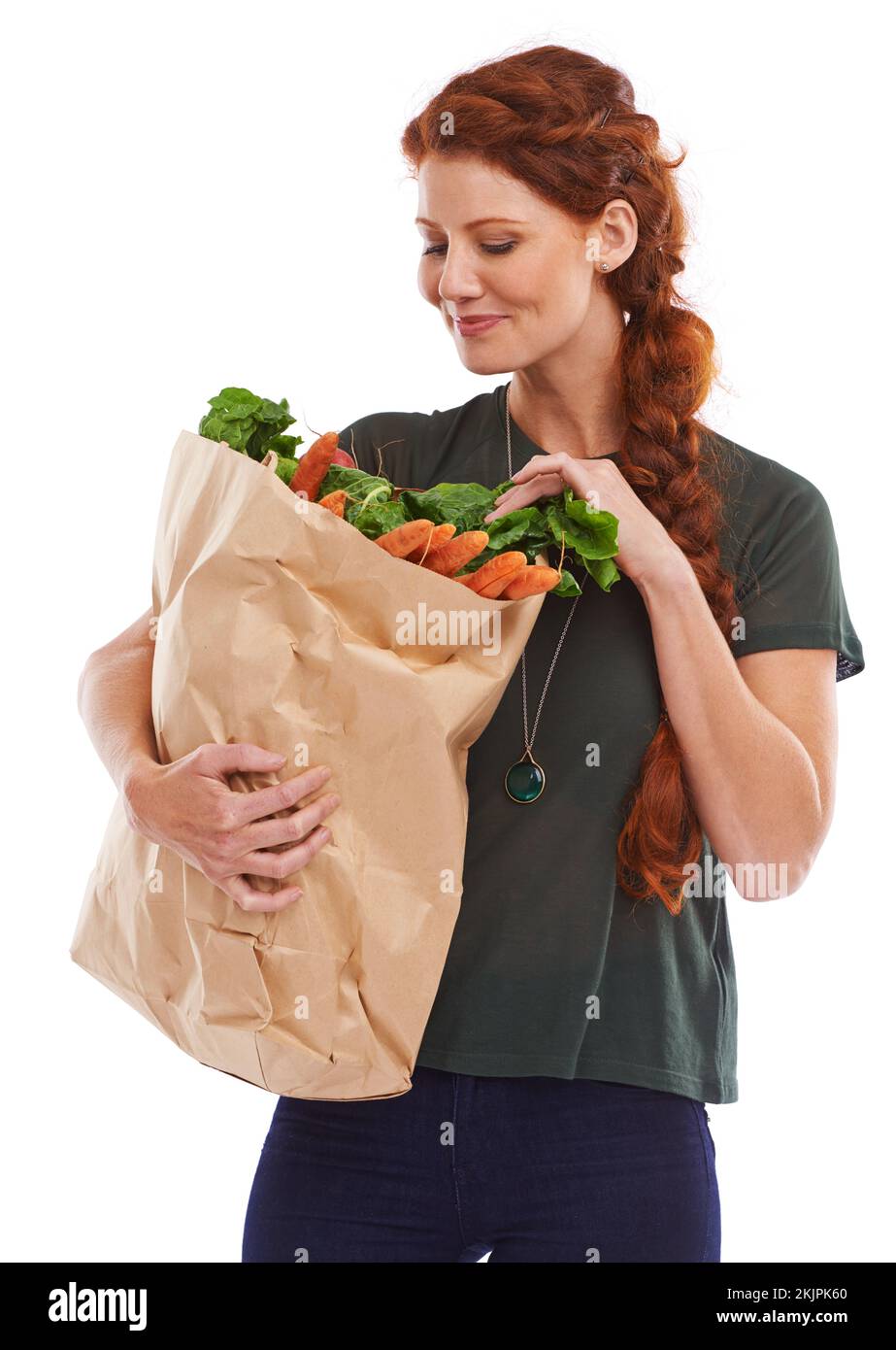 Hmmm... what am I going to do with these. Studio shot of a beautiful young woman holding a shopping bag full of fresh vegetables. Stock Photo