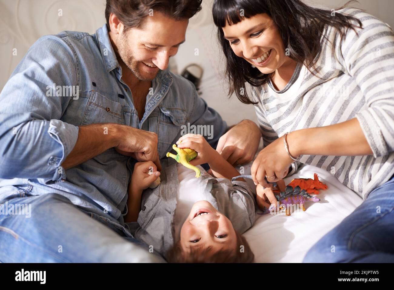 Tummy tickles. happy parents bonding with their son at home Stock Photo - Alamy