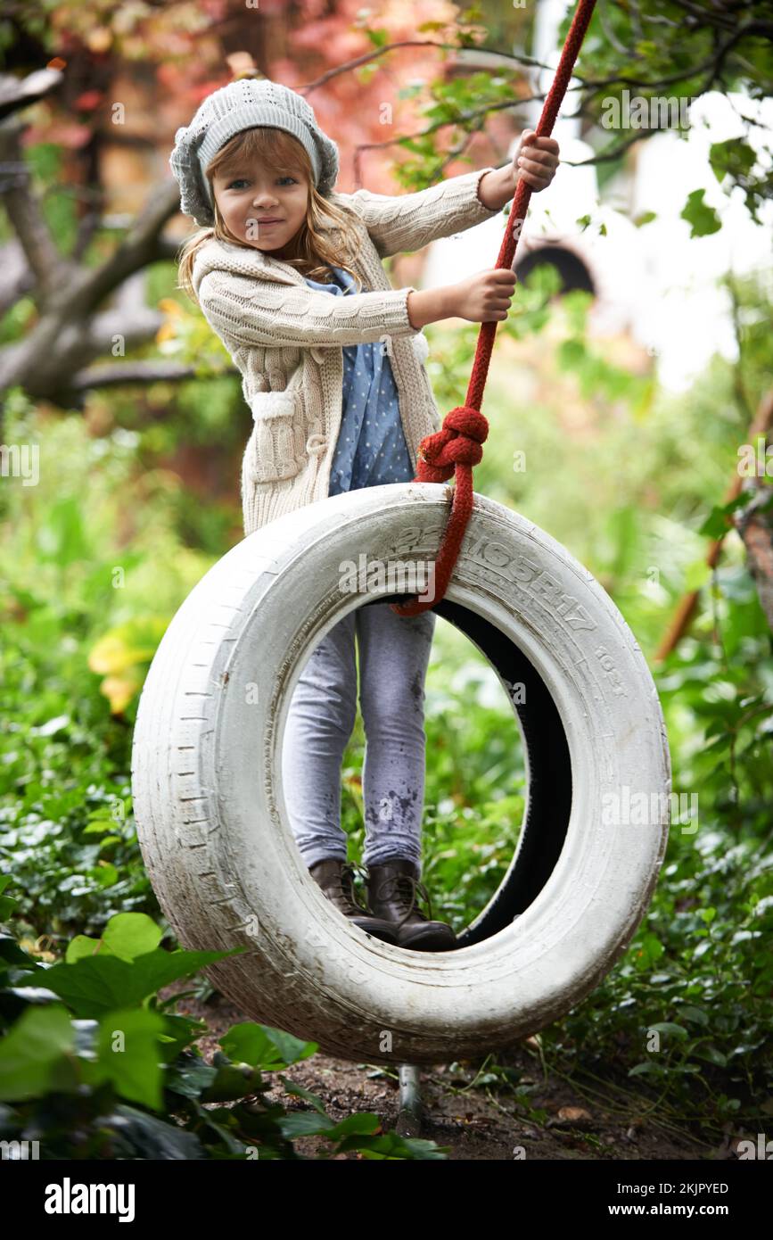 Her favourite part of the garden. Portrait of a cute little girl playing on a tire swing in the garden. Stock Photo