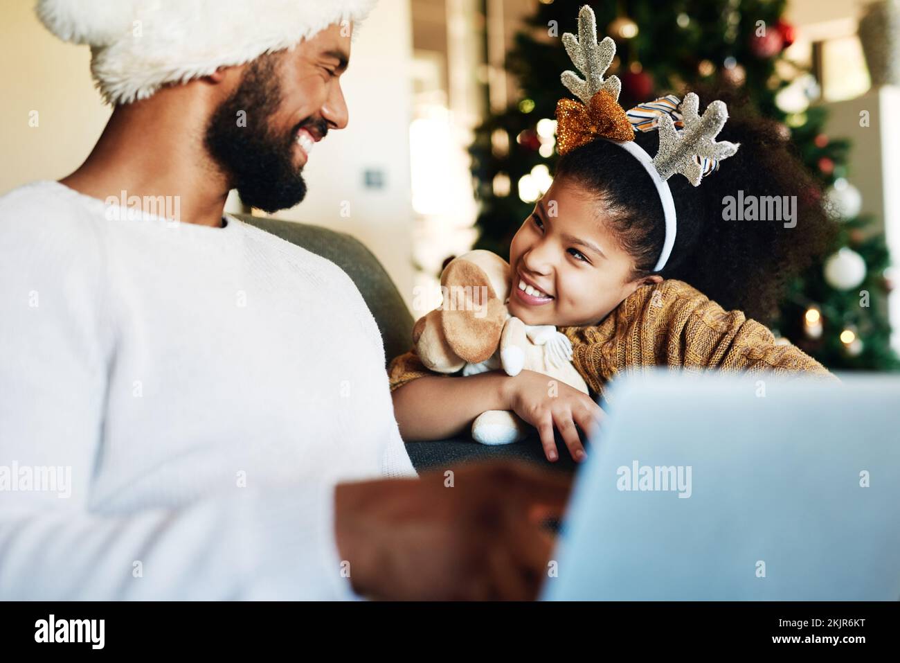 Family, laptop and relax for christmas celebration on sofa in living room, girl and father together to celebrate holiday with xmas tree. Black family Stock Photo