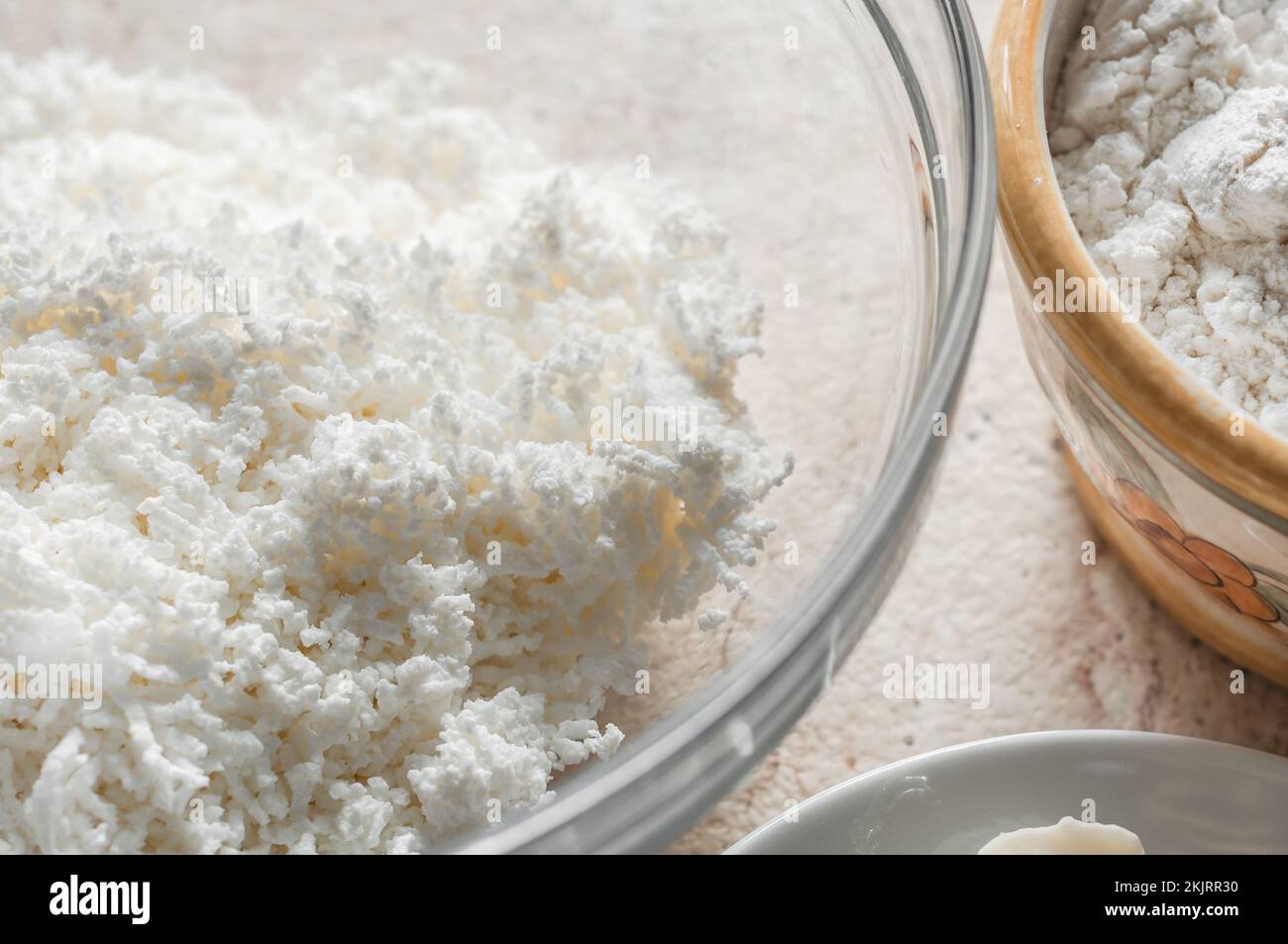 A strained curd in a glass bowl, a cup of flour on a ceramic tile Stock