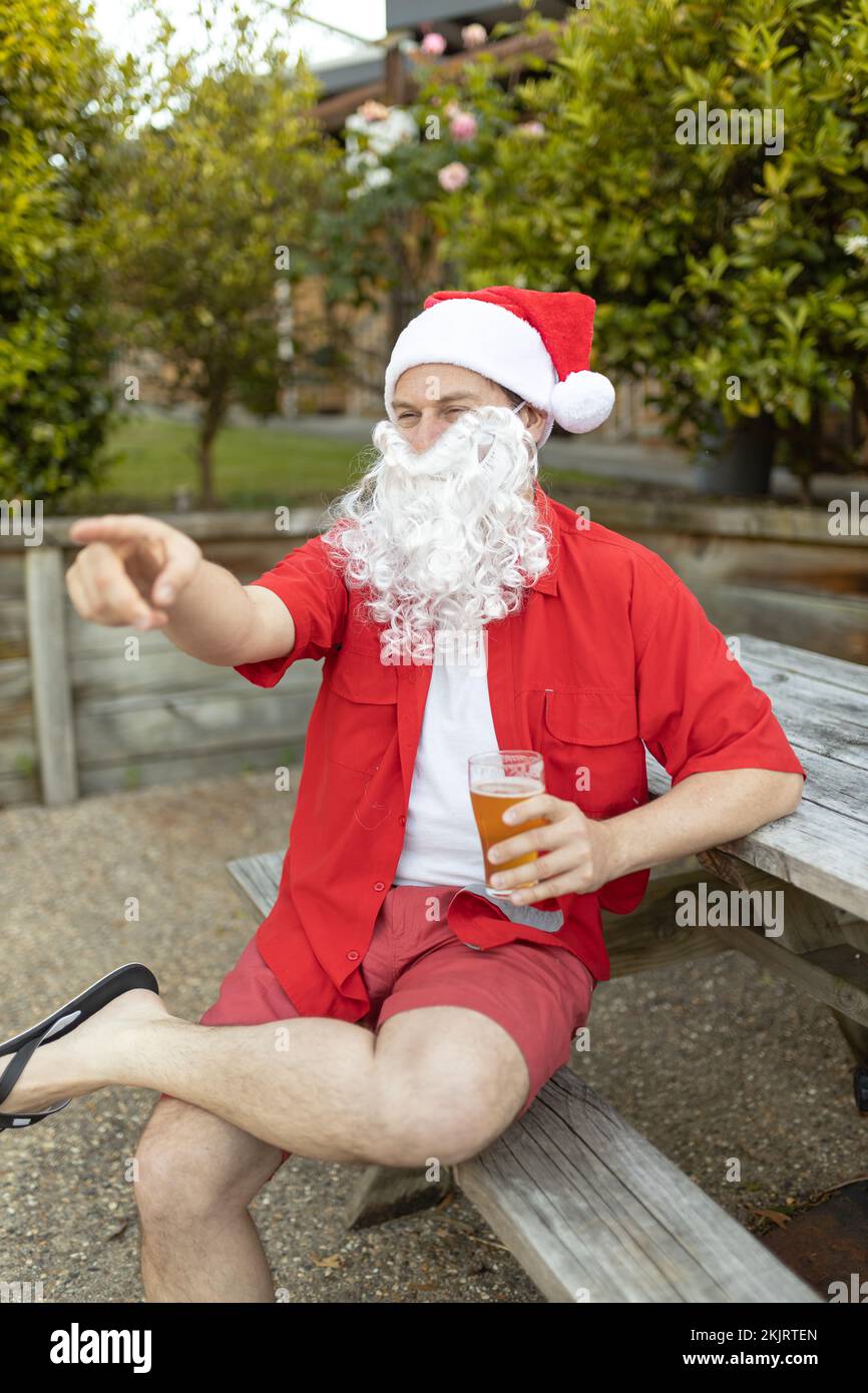 A Santa Claus at Christmas time in  the Australian summer holding a beer Stock Photo