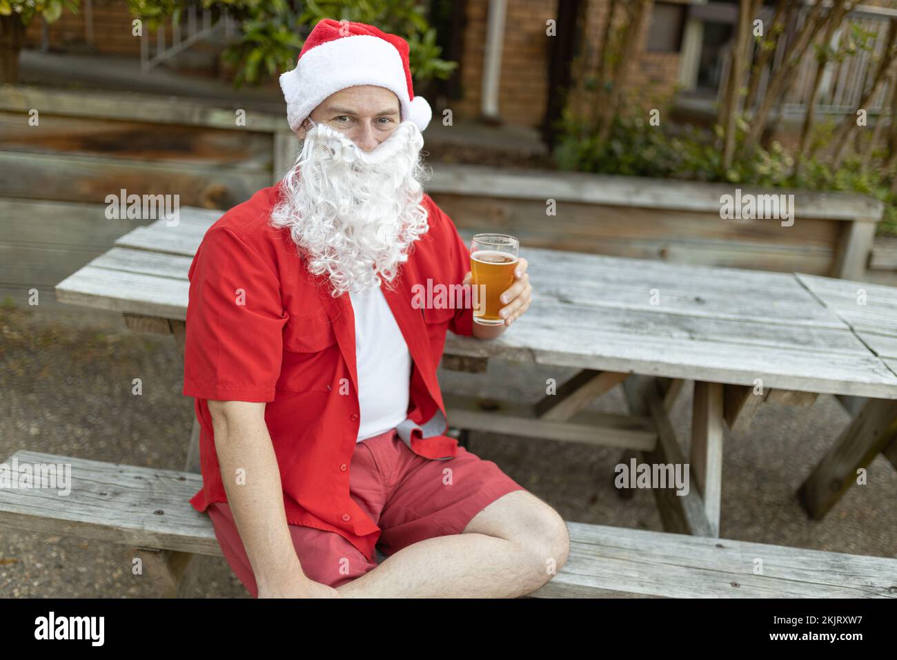 A Santa Claus at Christmas time in  the Australian summer holding a beer Stock Photo