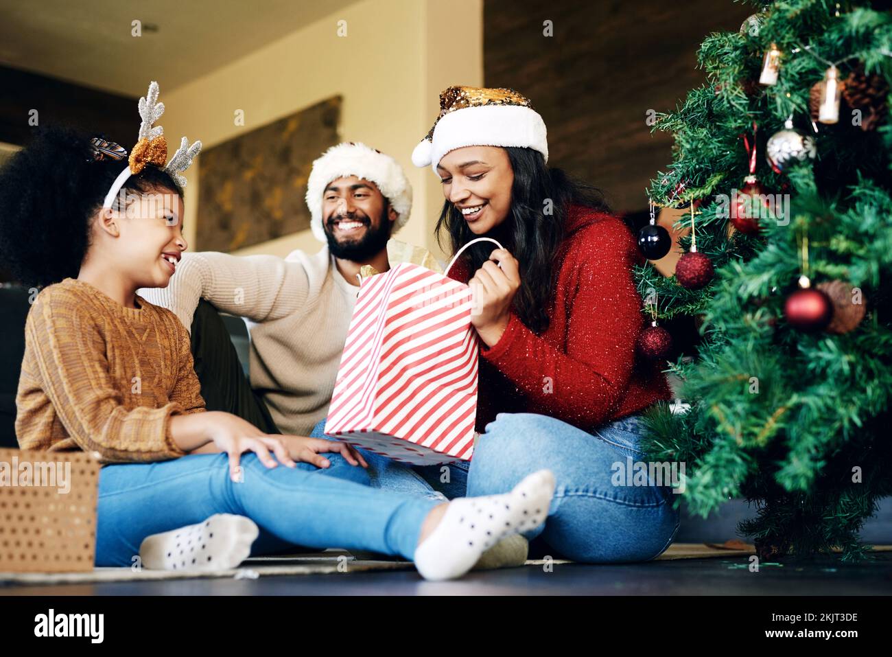 Christmas, love and family opening gifts in home, having fun and bonding on holiday. Xmas spirit, care and happy father, mother and girl exchange Stock Photo