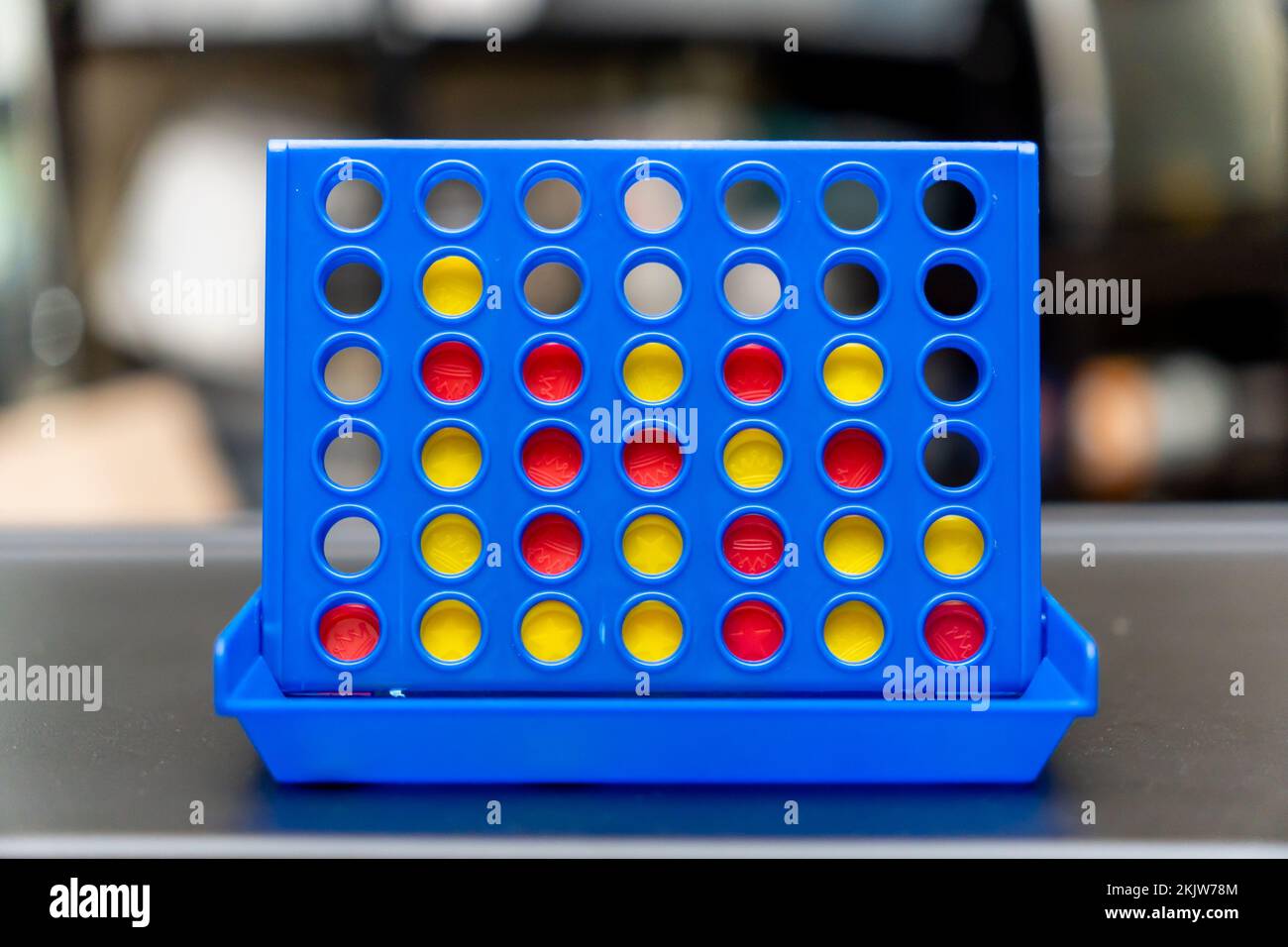 A selective focus shot of a blue Connect 4 game board with yellow and red tokens Stock Photo
