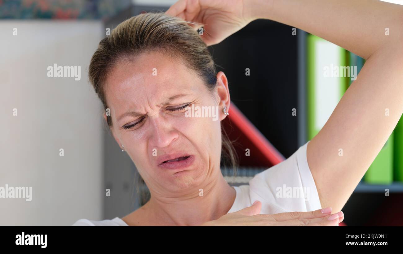 Female sniffing armpits and feeling of revulsion because of smell Stock Photo