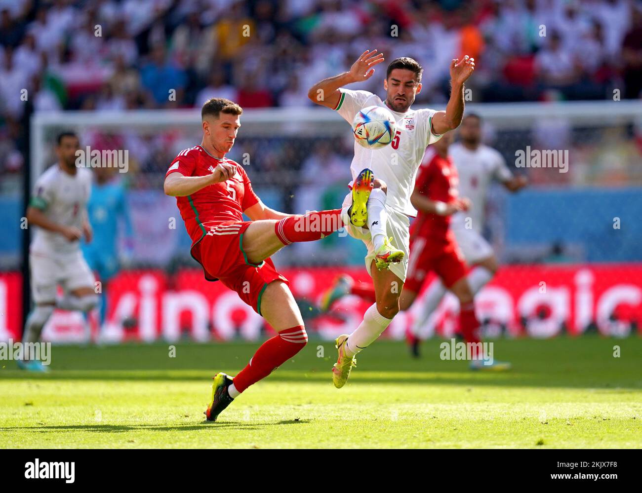 Wales' Chris Mepham (left) and Iran's Milad Mohammadi battle for the ball during the FIFA World Cup Group B match at the Ahmad Bin Ali Stadium, Al-Rayyan. Picture date: Friday November 25, 2022. Stock Photo