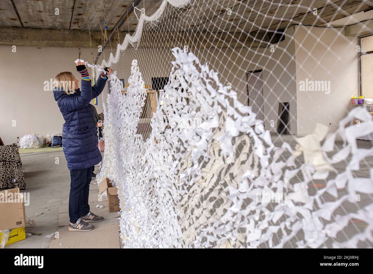 MUKACHEVO, UKRAINE - NOVEMBER 22, 2022 - Volunteer Oksana Dychka makes a camouflage net for the Ukrainian Armed Forces at the Venetsiia volunteer hub, Stock Photo