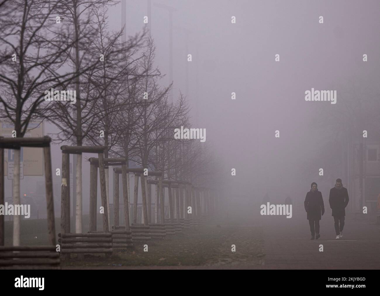 PRODUCTION - 25 November 2022, Berlin: Passers-by walk along a foggy sidewalk on Karl-Marx-Allee in the morning. Photo: Monika Skolimowska/dpa Stock Photo