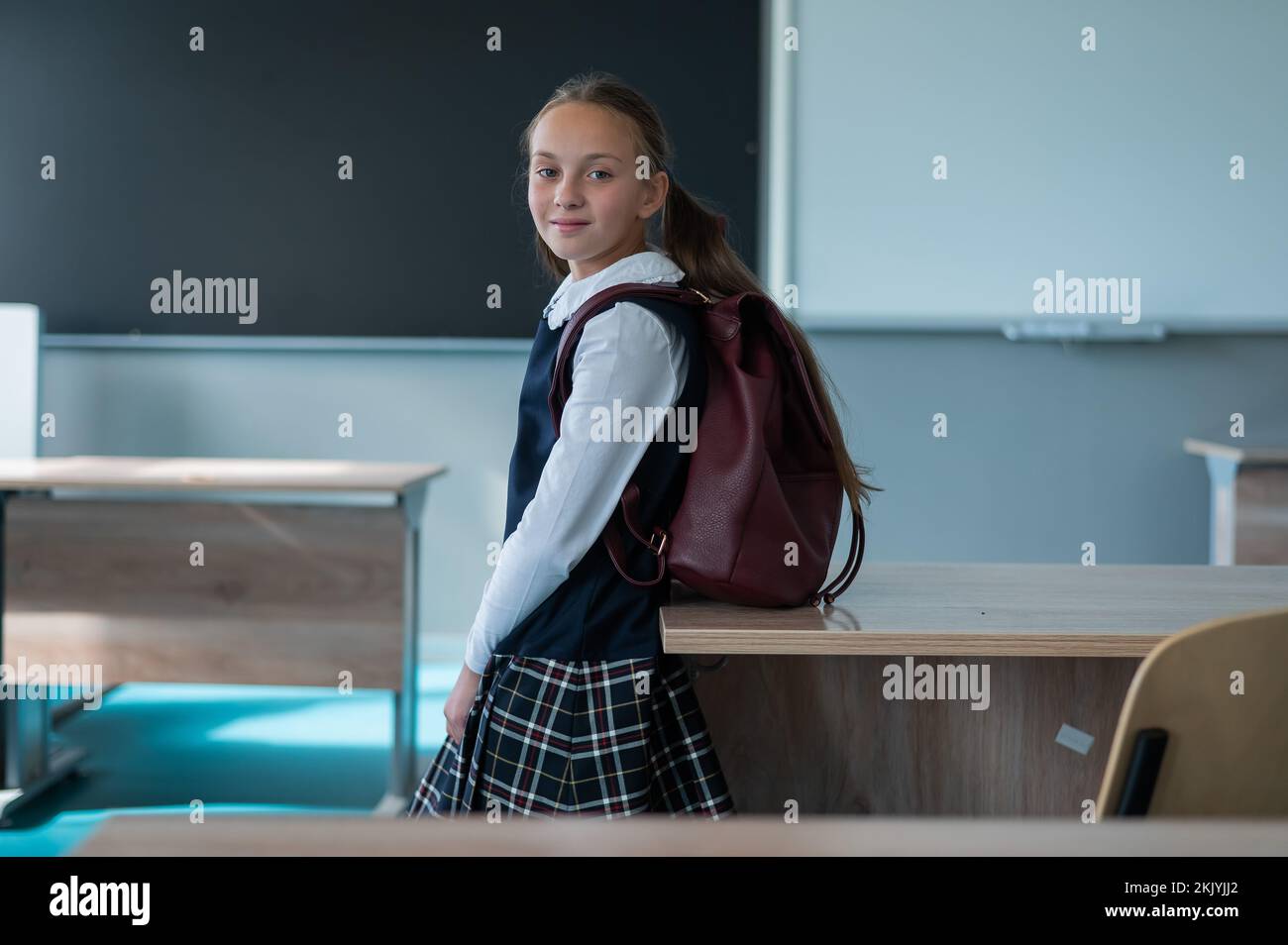 Portrait of a caucasian schoolgirl with a backpack in the classroom on ...