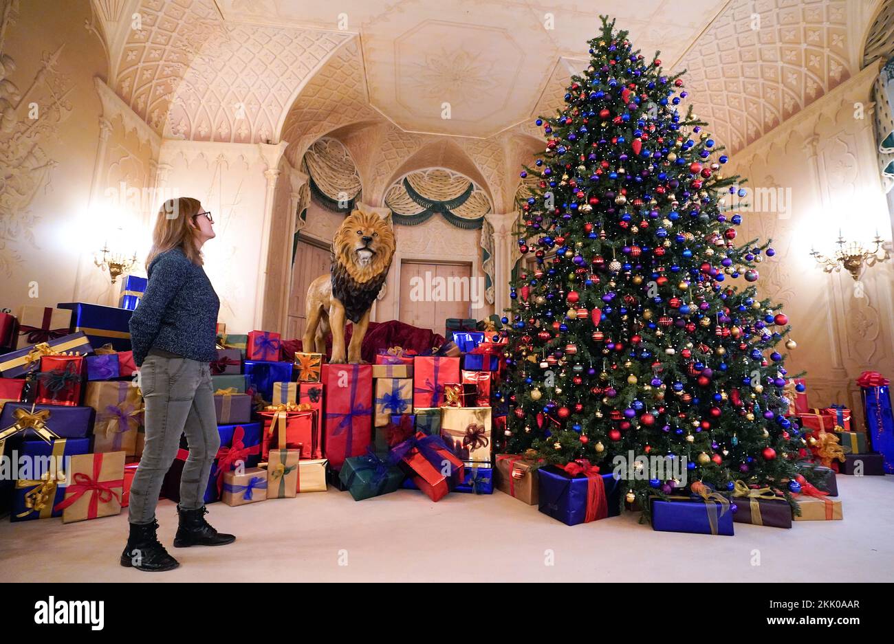 A staff member at the National Trust's Mottisfont near Romsey in Hampshire looks up at a Christmas tree inside the Whistler Room which has been transformed into a scene inspired by C.S. Lewis’s The Lion, the Witch and the Wardrobe, during a Christmas exhibition preview. Picture date: Friday November 25, 2022. Stock Photo