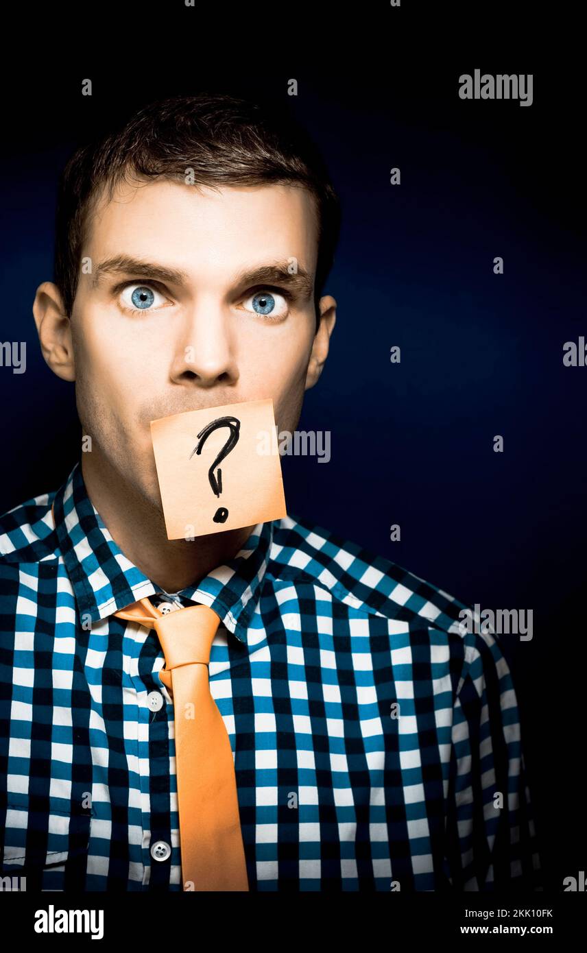 Young Male Business Person In Need Of Help With A Stick Note Question Mark Over His Face In A WTF Conceptual Of Being Left Out In The Dark Stock Photo