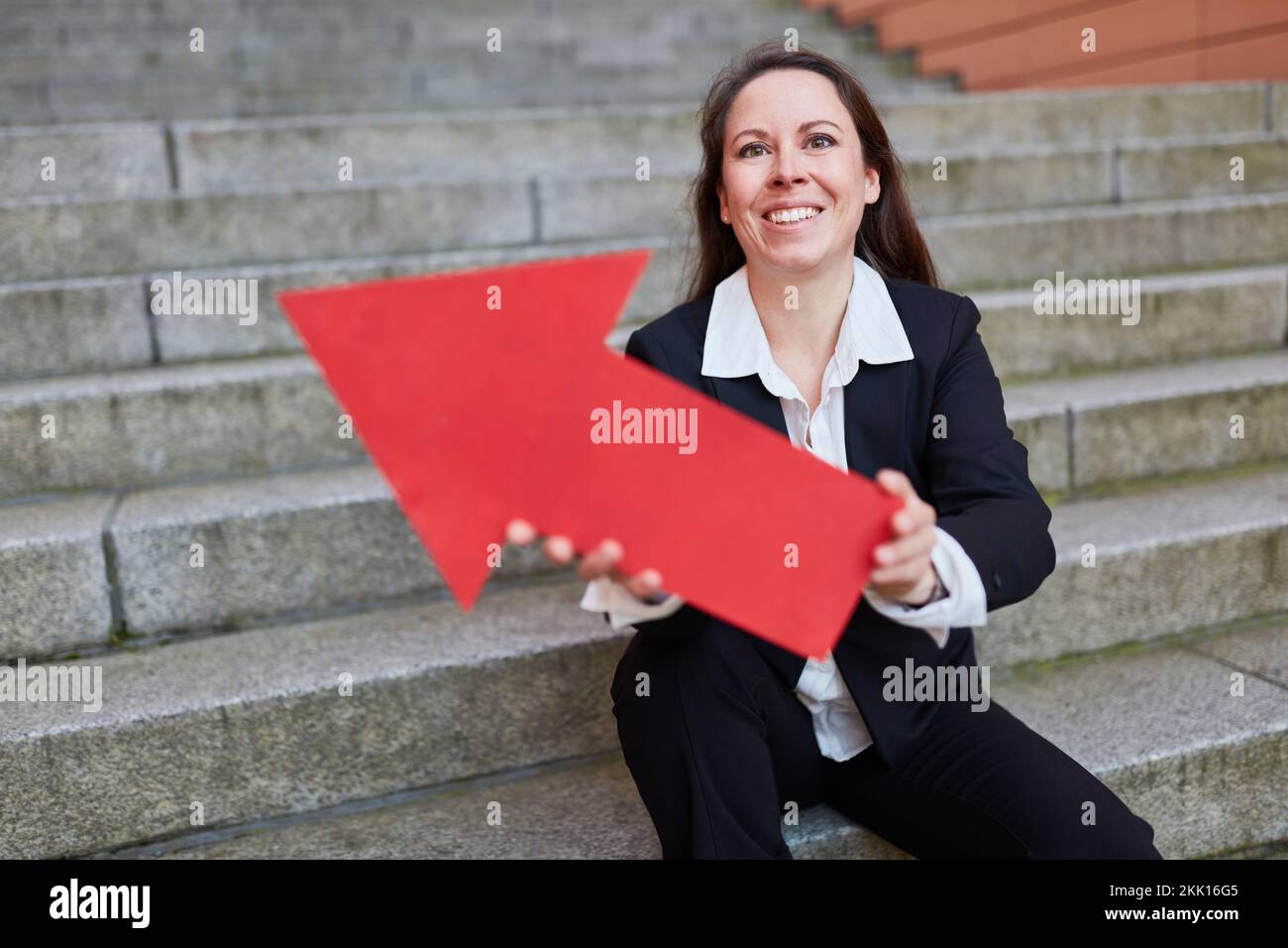 Confident businesswoman holding red arrow symbol as career and success ...