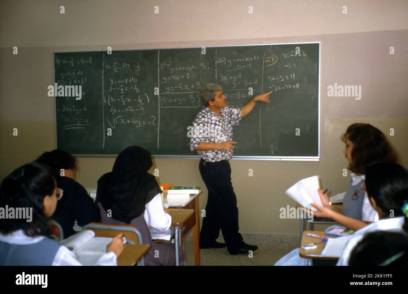 Abu Dhabi UAE High School Teacher at Blackboard Teaching Maths to Students Stock Photo