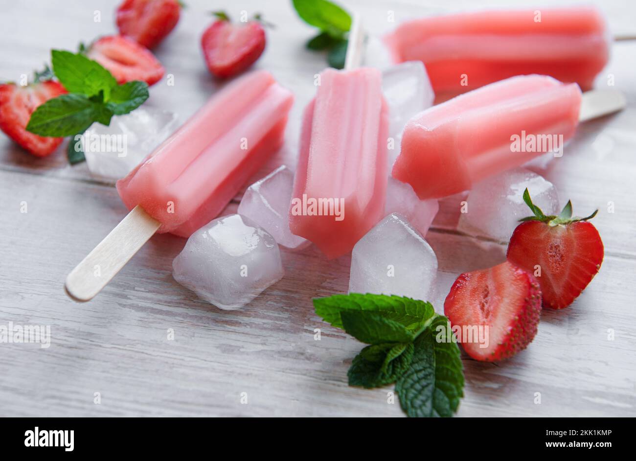 Homemade frozen strawberry ice cream popsicles and fresh strawberries
