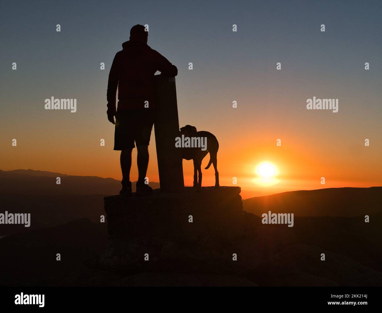 The silhouette of a man on the peak of a mountain and admiring the ...