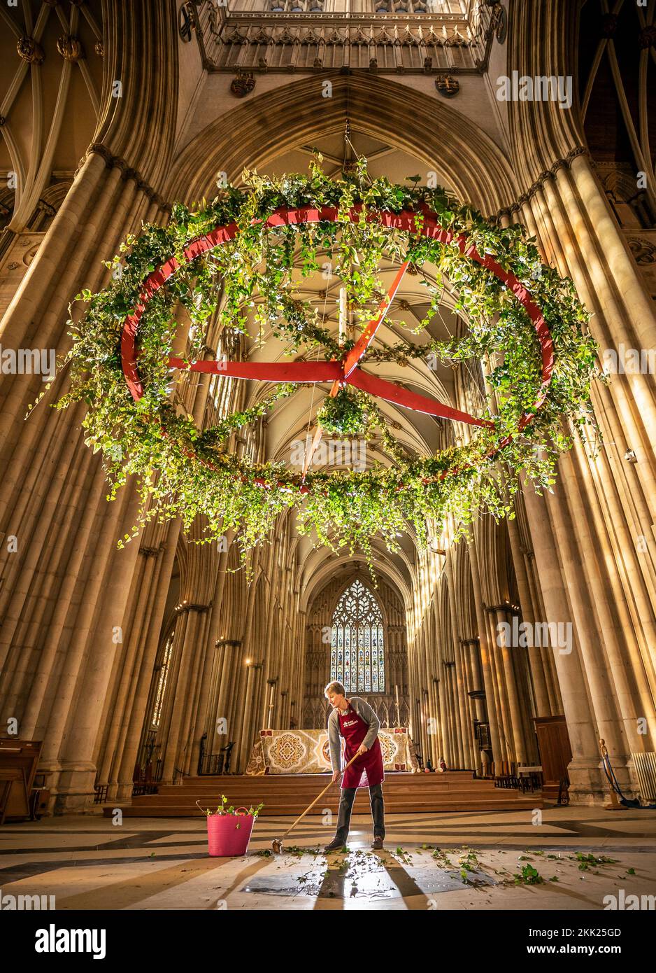 Mandy Barker sweeps foliage from the floor after putting the finishing touches to the Advent wreath before it is raised to its traditional position below the Central Tower at York Minster. Picture date: Friday November 25, 2022. Stock Photo