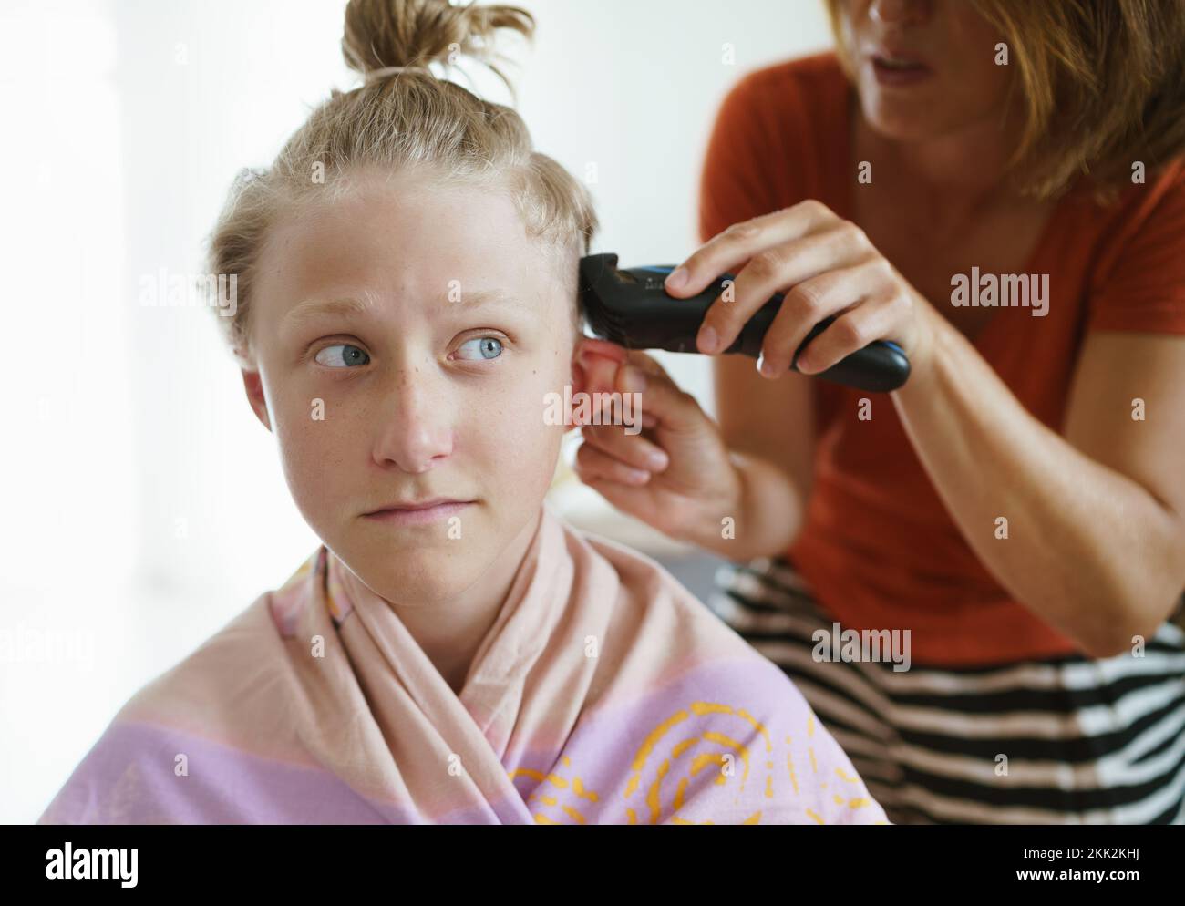Mother trimming her son hairs making a modern hairstyle using electric