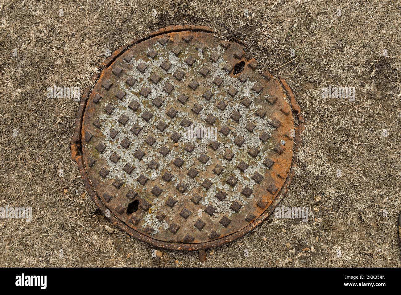 Metal cast iron water inspection hatch flush with bleached sun drought