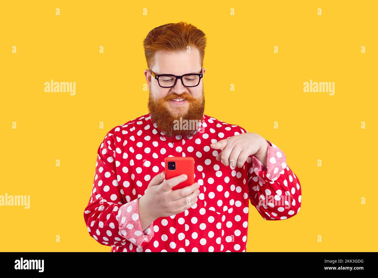 Cheerful bearded chubby man enjoys using mobile application installed in his modern smartphone. Stock Photo