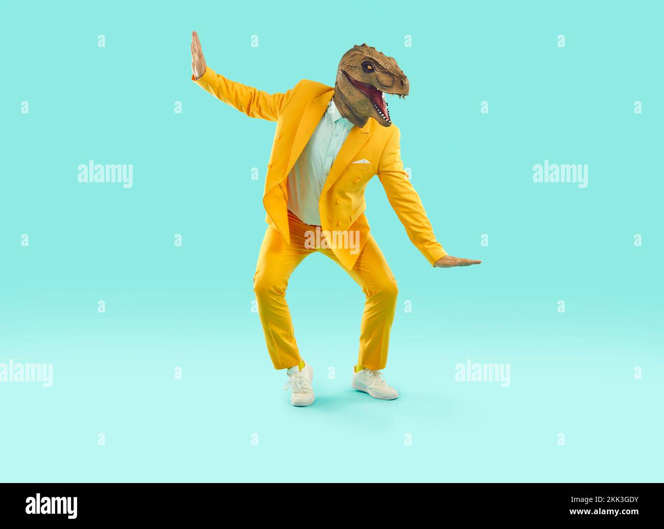 Funny Man In A Yellow Party Suit And A Dinosaur Mask Dancing On A Blue funny-man-in-a-yellow-party-suit-and-a-dinosaur-mask-dancing-on-a-blue