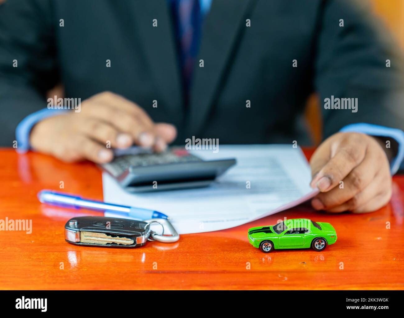 Model car and car key paste on the wooden table, saleman caculate car